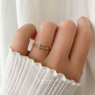 Statement Grey gold ring featuring an aqua opal blossom, vine leaves, and sparkling CZ stones on a finger.